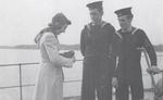 Oakville student taking a picture of two HMCS Oakville crew members, November 5, 1941